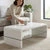 A woman placing a coffee cup on the Arch High Gloss Coffee Table White in a modern living room setting.